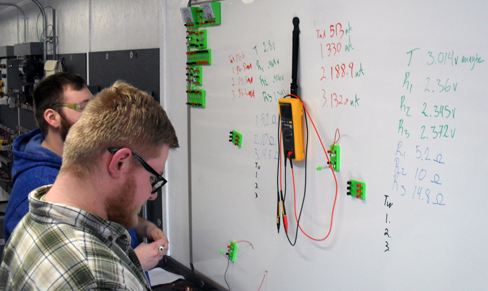 Students working out an electrial issues on a whiteboard.